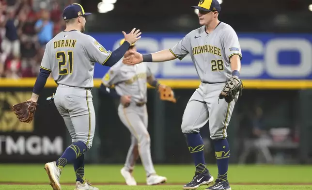 Milwaukee Brewers' Caleb Durbin, left, and Milwaukee Brewers' Andrew Vaughn, right, celebrate their win at the conclusion of the ninth inning of a baseball game against the Cincinnati Reds, Friday, Aug. 15, 2025, in Cincinnati. (AP Photo/Kareem Elgazzar)