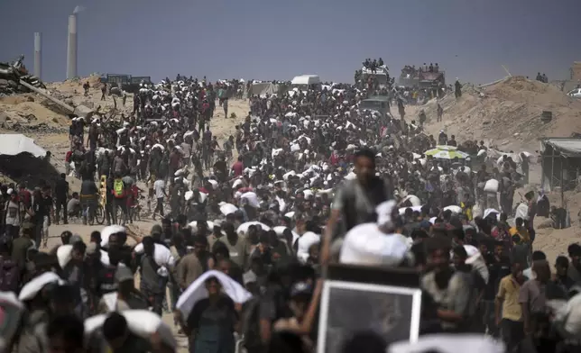 Palestinians carry sacks of flour taken from a humanitarian aid convoy en route to Gaza City, in the outskirts of Beit Lahiya, northern Gaza Strip, Friday, Aug. 1, 2025. (AP Photo/Jehad Alshrafi)