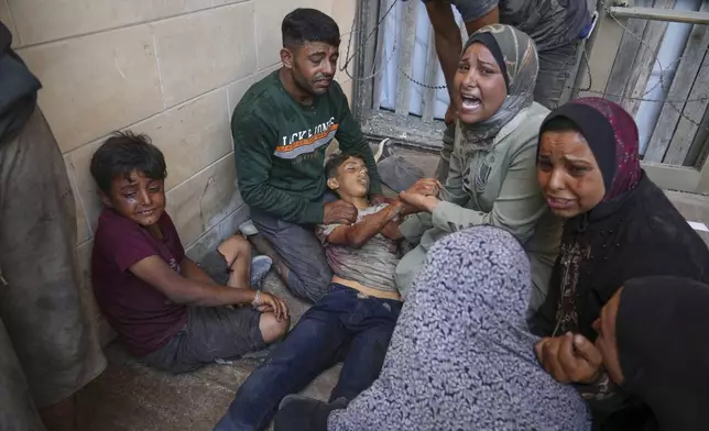 People mourn over the body of a young Palestinian killed while trying to reach trucks carrying humanitarian aid en route to Gaza City, outside the Hamad Al-Qatari Hospital in Beit Lahiya, northern Gaza Strip, Friday, Aug. 1, 2025. (AP Photo/Jehad Alshrafi)