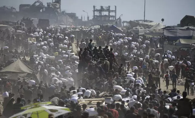 Palestinians carry sacks of flour taken from a humanitarian aid convoy en route to Gaza City, in the outskirts of Beit Lahiya, northern Gaza Strip, Friday, Aug. 1, 2025. (AP Photo/Jehad Alshrafi)