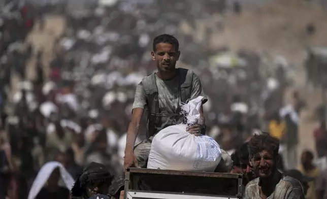 Palestinians carry sacks of flour taken from a humanitarian aid convoy en route to Gaza City, in the outskirts of Beit Lahiya, northern Gaza Strip, Friday, Aug. 1, 2025. (AP Photo/Jehad Alshrafi)