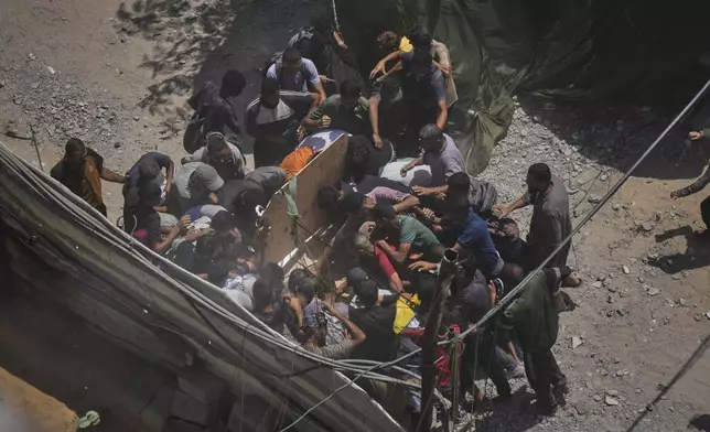 Palestinians struggle to collect humanitarian aid airdropped by parachutes into Gaza City, northern Gaza Strip, Thursday, Aug. 7, 2025. (AP Photo/Jehad Alshrafi)
