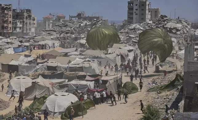 Palestinians rush to collect humanitarian aid airdropped by parachutes into Gaza City, northern Gaza Strip, Thursday, Aug. 7, 2025. (AP Photo/Jehad Alshrafi)