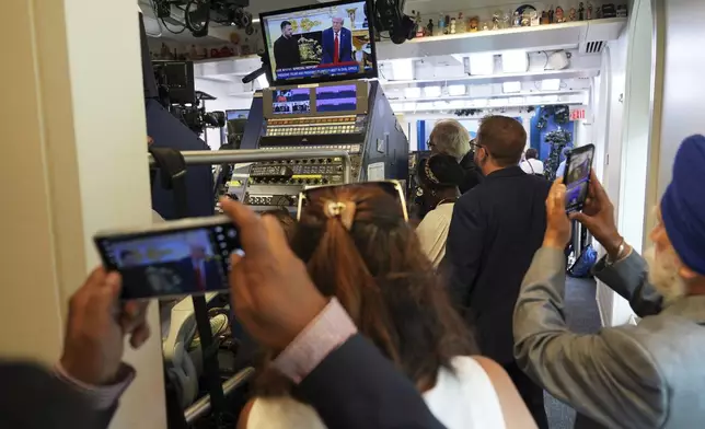 Members of the media watch a live feed as President Donald Trump, pictured on screen at right, meets with Ukraine's President Volodymyr Zelenskyy, Monday, Aug. 18, 2025, at the White House in Washington. (AP Photo/Jacquelyn Martin)