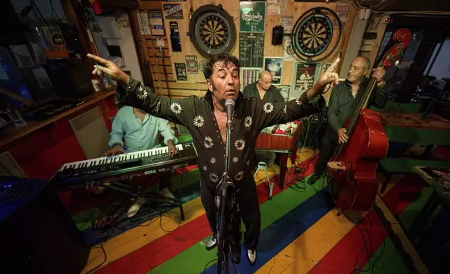 Tudor Lakatos, who goes by the stage name Elvis Rromano, performs at the Terasa Florilor restaurant along with Nicolae Feraru, center, Stelian Frunza, left, and Stefan Marin, right, of the Taraful Frunzelor band, in Bucharest, Romania, Friday, June 20, 2025. (AP Photo/Andreea Alexandru)