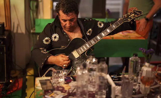 Tudor Lakatos, who goes by the stage name Elvis Rromano, tunes his guitar during a performance at the Terasa Florilor restaurant in Bucharest, Romania, Friday, June 20, 2025. (AP Photo/Vadim Ghirda)