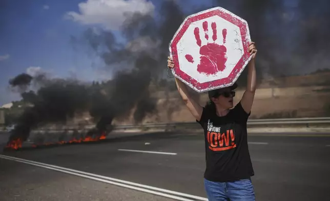 A demonstrator blocks a highway during a protest demanding the immediate release of all hostages held by Hamas and calling for the end of the war in the Gaza Strip, near Modiin, Israel, Tuesday, Aug. 26, 2025. (AP Photo/Ohad Zwigenberg)