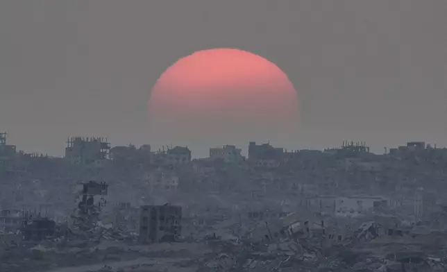The sun sets behind buildings destroyed during Israeli ground and air operations in the Gaza Strip, as seen from southern Israel, Tuesday, Aug. 26, 2025. (AP Photo/Maya Levin)