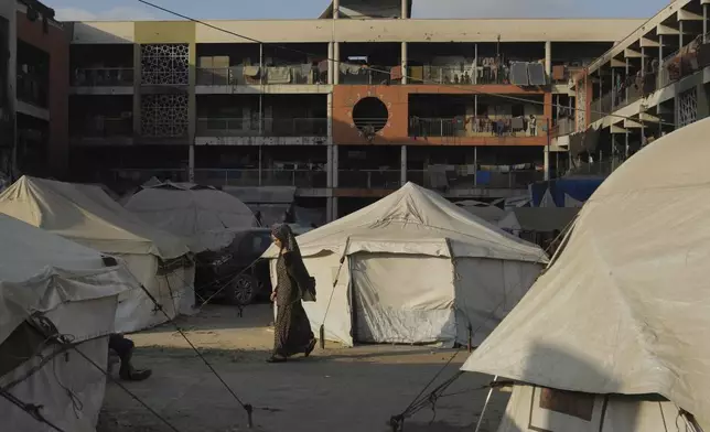 A Palestinian woman walks past tents for displaced people in a school used as a shelter in Gaza City, Wednesday, Aug. 27, 2025. (AP Photo/Jehad Alshrafi)