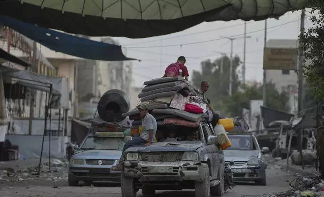 Displaced Palestinians fleeing Jabaliya move with their belongings on a street in Gaza City, Tuesday, Aug. 26, 2025. (AP Photo/Jehad Alshrafi)