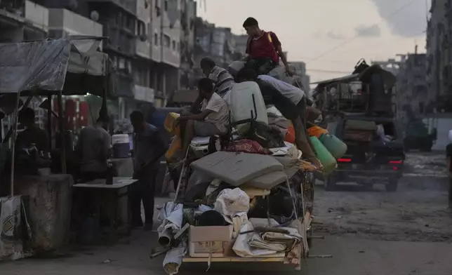 Displaced Palestinians fleeing Jabaliya move with their belongings on a street in Gaza City, Tuesday, Aug. 26, 2025. (AP Photo/Jehad Alshrafi)