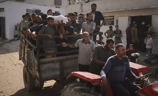 Palestinians carry the body of a person who was killed while trying to reach aid trucks entering northern Gaza Strip through the Zikim crossing with Israel, at Shifa Hospital in Gaza City, Wednesday, Aug. 6, 2025. (AP Photo/Jehad Alshrafi)