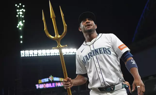 Seattle Mariners' Julio Rodriguez holds the trident to celebrate a win over the Tampa Bay Rays in a baseball game Saturday, Aug. 9, 2025, in Seattle. (AP Photo/Lindsey Wasson)