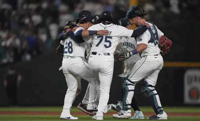 Seattle Mariners relief pitcher Andrés Muñoz (75) celebrates a win over the Tampa Bay Rays with the infield, including third baseman Eugenio Suarez (28) after a baseball game Saturday, Aug. 9, 2025, in Seattle. (AP Photo/Lindsey Wasson)