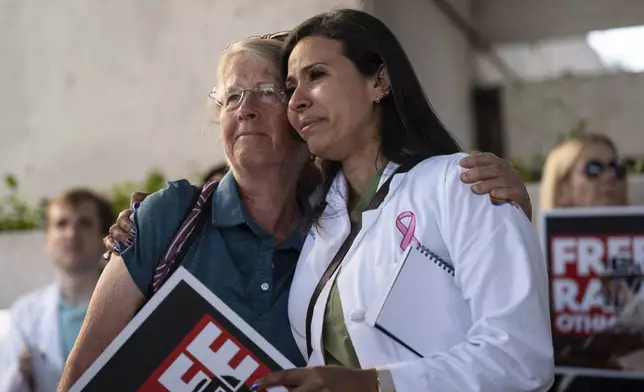 Dr. Wafaa Alrashid, right, whose husband, Rami Othmane, a Tunisian musician, is detained at the U.S. Immigration and Customs Enforcement facility, is comforted by Dr. Kimberly Shriner during a rally outside the facility in Los Angeles Friday, July 25, 2025. (AP Photo/Jae C. Hong)