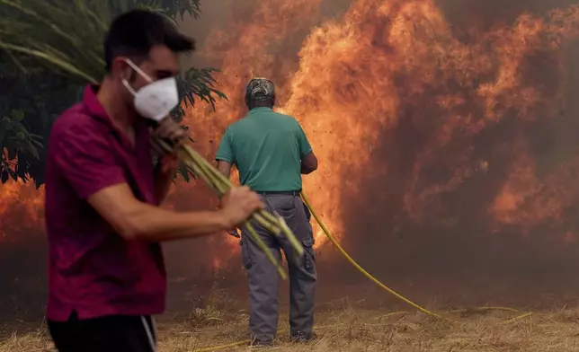 Residents battle a fire advancing toward Rebordondo village, near Ourense, in northwestern Spain, on Monday, Aug. 18, 2025. (AP Photo/Pablo Garcia)
