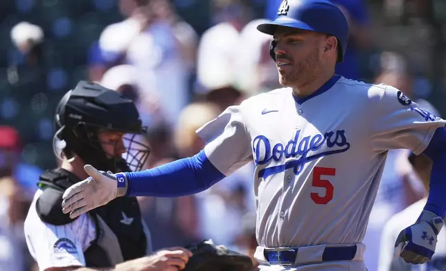 Los Angeles Dodgers' Freddie Freeman is congratulated as he crosses home plate after hitting a two-run home run off Colorado Rockies starting pitcher Chase Dollander in the first inning of a baseball game Thursday, Aug. 21, 2025, in Denver. (AP Photo/David Zalubowski)