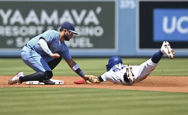 Los Angeles Dodgers' Mookie Betts, right, is tagged out by Toronto Blue Jays shortstop Bo Bichette, left, on a steal-attempt during the first inning of a baseball game Sunday, Aug. 10, 2025, in Los Angeles. (AP Photo/Wally Skalij)