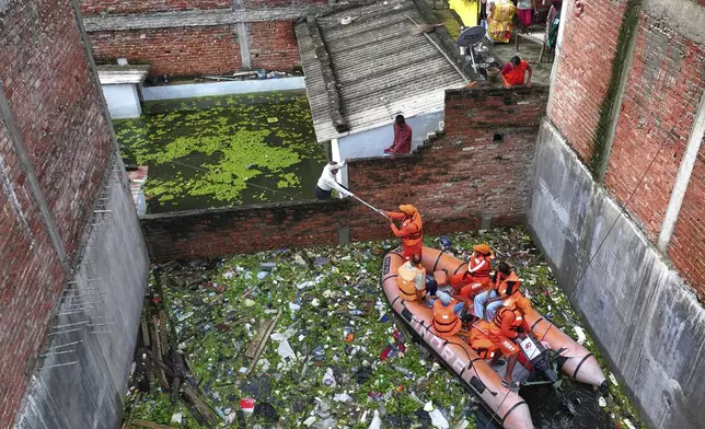 Members of India's National Disaster Response Force distribute food supplies to stranded residents in a submerged area following heavy monsoon rains along the banks of the River Ganga, in Prayagraj, India, Aug. 5, 2025. (AP Photo/Rajesh Kumar Singh)