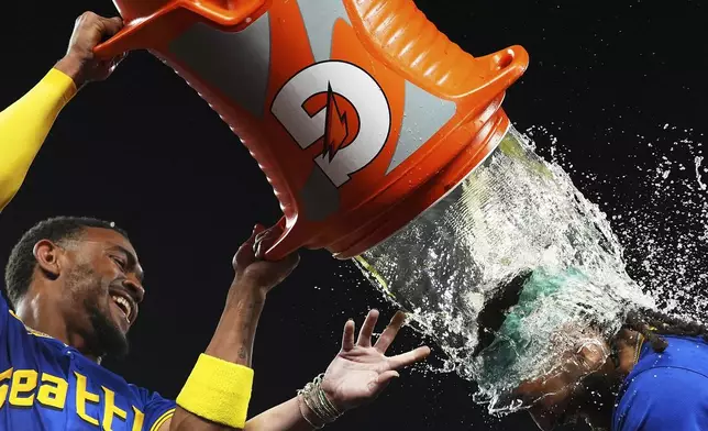 Seattle Mariners' Julio Rodriguez, left, douses J.P. Crawford after Crawford hit a game-winning home run to beat the Texas Rangers in a baseball game in Seattle, Aug. 1, 2025. (AP Photo/Lindsey Wasson)