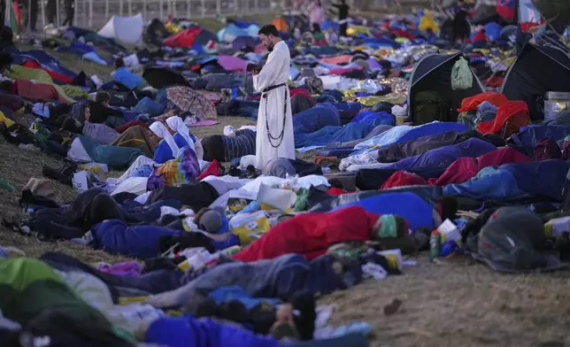 A priest stands amid young people camping out on the Tor Vergata field, before the start of a Mass led by Pope Francis celebrating the Jubilee of the Catholic Church, in Rome, Aug. 3, 2025. (AP Photo/Andrew Medichini)