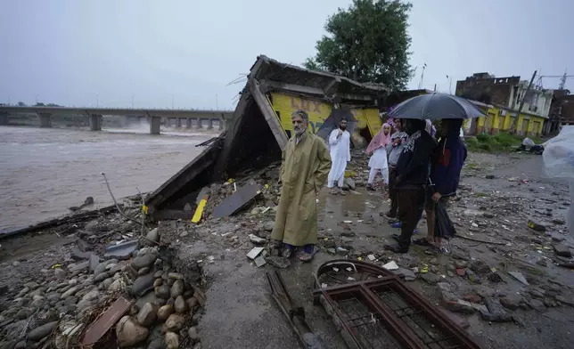 Residents look at the remains of their houses, damaged by flash floods at the banks of Tawi river in Jammu, India, Wednesday, Aug. 27, 2025. (AP Photo/Channi Anand)