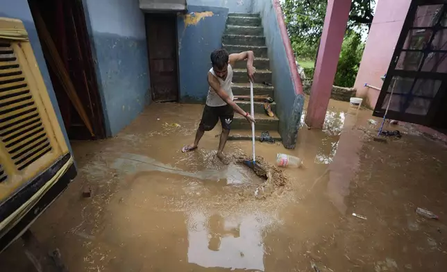 A man removes mud from his home after it was hit by flash floods on the outskirts of Jammu, India, Sunday, Aug. 24, 2025. (AP Photo/Channi Anand)