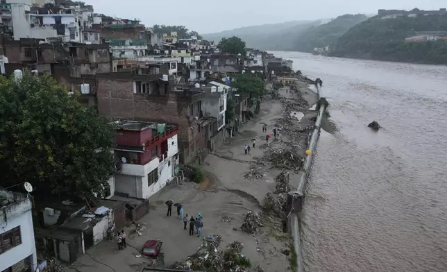 Residents check the damage caused to their house by flash floods at banks of Tawi river in Jammu, India, Wednesday, Aug. 27, 2025. (AP Photo/Channi Anand)