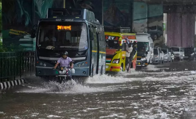 Commuters move through a flooded road after heavy rain in Jammu, India, Tuesday, Aug. 26, 2025.(AP Photo/Channi Anand)