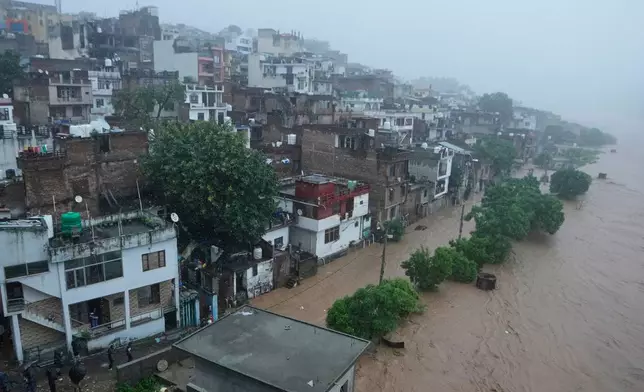 People watch a swelling River Tawi from the roof of their houses in Jammu, India, Tuesday, Aug 26, 2025.(AP Photo/Channi Anand)