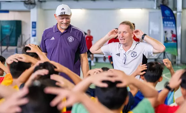 Manchester United legend Peter Schmeichel (left) joins the Manchester United Academy U16 team and Hong Kong, China U16 Representative Team in community service, helping primary school students brush up their football skills at the Sha Tin Racecourse Sports Ground.