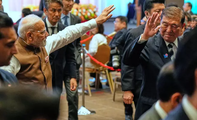 Indian Prime Minister Narendra Modi, left, and Japanese Prime Minister Shigeru Ishiba, right, wave as they leave the venue of the Japan India Economic Forum in Tokyo Friday, Aug. 29, 2025. (AP Photo/Eugene Hoshiko)