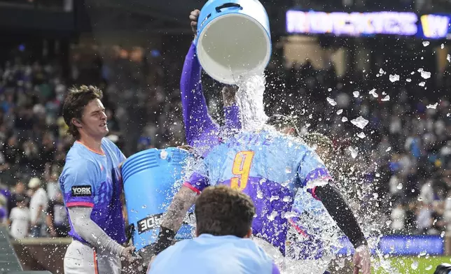 Colorado Rockies' Mickey Moniak, back left, and Orlando Arcia, back right, douse Brenton Doyle (9) after Doyle hit a two-run wakoff home run off Pittsburgh Pirates relief pitcher Dennis Santana in the ninth inning of a baseball game Friday, Aug. 1, 2025, in Denver. (AP Photo/David Zalubowski)