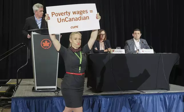 Air Canada executives are interrupted by Air Canada flight attendants during a news conference as a possible strike looms, in Toronto, on Thursday, Aug. 14, 2025. (Nathan Denette/The Canadian Press via AP)