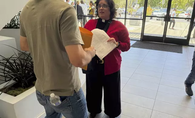 The Rev. Oona Casanova Vazquez, lead pastor of the South Bay Church of the Nazarene in Torrance, speaks with a man she is about to accompany to a hearing in Santa Ana Immigration Court in Santa Ana, Calif., Thursday, July 31, 2025. (AP Photo/Deepa Bharath)