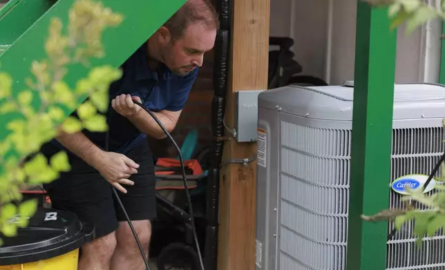 Craig Keenan runs a wire to an outlet after installing a solar panel from Bright Saver on Friday, Aug. 1, 2025, in Baltimore. (AP Photo/KT Kanazawich)