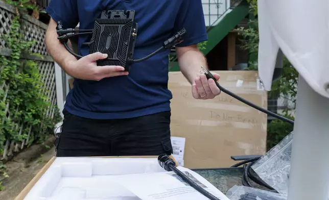 Craig Keenan prepares to install a microinverter with his solar panel from Bright Saver on Friday, Aug. 1, 2025, in Baltimore. (AP Photo/KT Kanazawich)