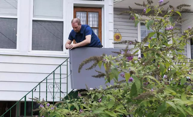 Craig Keenan installs a solar panel from Bright Saver on Friday, Aug. 1, 2025, in Baltimore. (AP Photo/KT Kanazawich)
