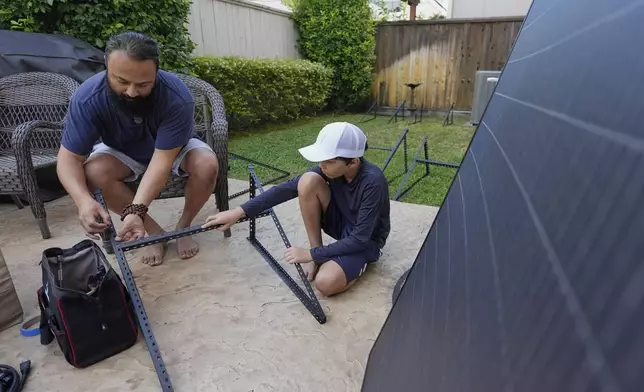 Bhavin Misra, left, and his son, Rumi, 10, assemble a Craftstrom Solar plug-in kit at their home Tuesday, Aug. 5, 2025, in Houston. (AP Photo/David J. Phillip)