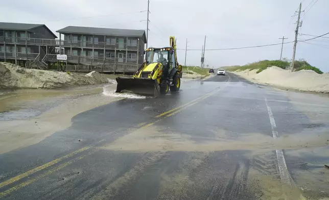 An front-end loader pushes sea water from Hurricane Erin down NC 12 in Buxton, N.C., on Wednesday, Aug. 20, 2025. (AP Photo/Allen G. Breed)