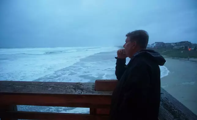 Greg Smrdel watches from Jennette's Pier as waves from Hurricane Erin crash ashore at dawn along Nags Head, N.C., on Thursday, Aug. 21, 2025. The Manteo, N.C., resident says he's been through many storms here, but averred Erin "is kind of cool." (AP Photo/Allen G. Breed)