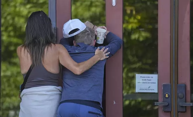 Kristen Neville, left, and Michael Burt cry and embrace each other at the doors of the Annunciation Catholic Church after Wednesday's school shooting, Thursday, Aug. 28, 2025, in Minneapolis. (AP Photo/Abbie Parr)