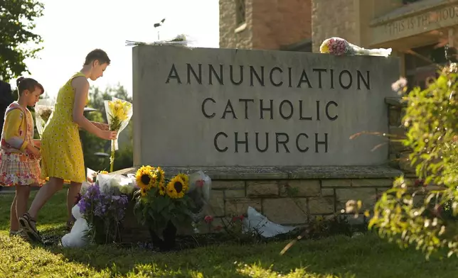 Ruth, right, and Sage place flowers at a memorial at Annunciation Catholic Church after Wednesday's school shooting, Thursday, Aug. 28, 2025, in Minneapolis. (AP Photo/Abbie Parr)
