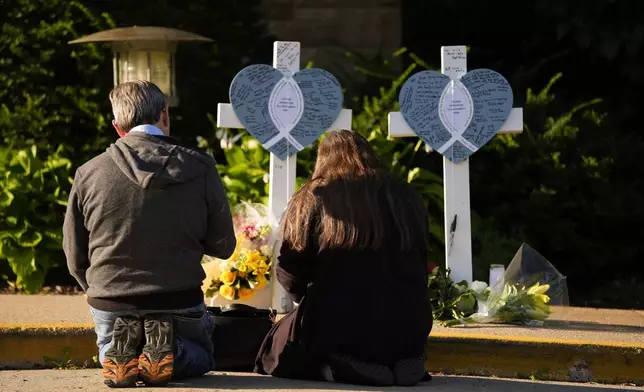 Tim and Katharine Barr kneel and pray at a memorial at Annunciation Catholic Church after Wednesday's school shooting, Thursday, Aug. 28, 2025, in Minneapolis. (AP Photo/Abbie Parr)