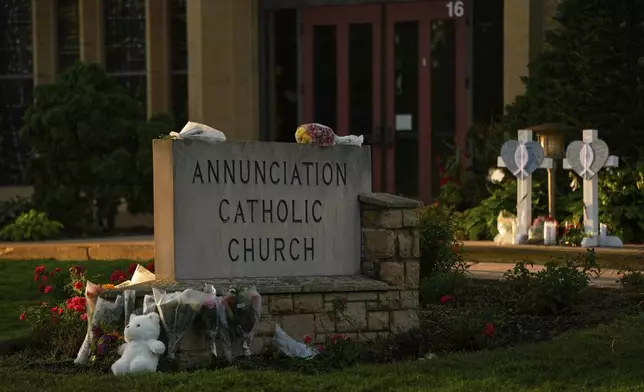 Crosses, flowers and other mementos were places by the sign at Annunciation Cathic Church at a memorial after Wednesday's shooting at the school, Thursday, Aug. 28, 2025, in Minneapolis. (AP Photo/Abbie Parr)