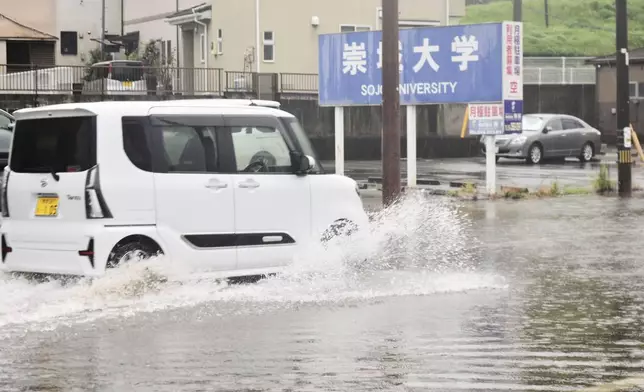 A vehicle advances through a flooded road in Kumamoto, southern Japan Monday, Aug. 11, 2025. (Kyodo News via AP)