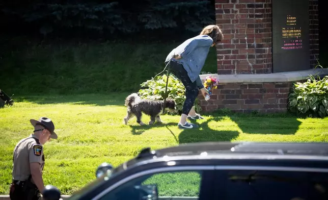 A woman is allowed to drop off flowers at the Annunciation Catholic School sign near the scene of a shooting at Annunciation Catholic Church, Wednesday, Aug. 27, 2025, in Minneapolis. (Renée Jones Schneider/Star Tribune via AP)