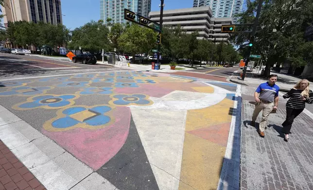 People walk past a street mural Wednesday, Aug. 27, 2025, in downtown Tampa, Fla. (AP Photo/Chris O'Meara)