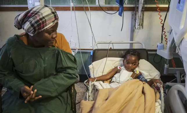 Vimbainashe Chakanungwa, left, watches on as her 9 year-old daughter Graciuos Chikovo sits on the chair as she recovers as she recovers from an open-heart surgery at Parirenyatwa Hospital, Harare, Zimbabwe, Thursday, July 17, 2025. (AP Photo/Aaron Ufumeli)