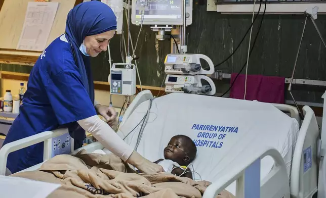 A doctor checks on a Anashe Mugoba as she recovers from an open-heart surgery at Parirenyatwa Hospital, Harare, Zimbabwe, Thursday, July 17, 2025. (AP Photo/Aaron Ufumeli)